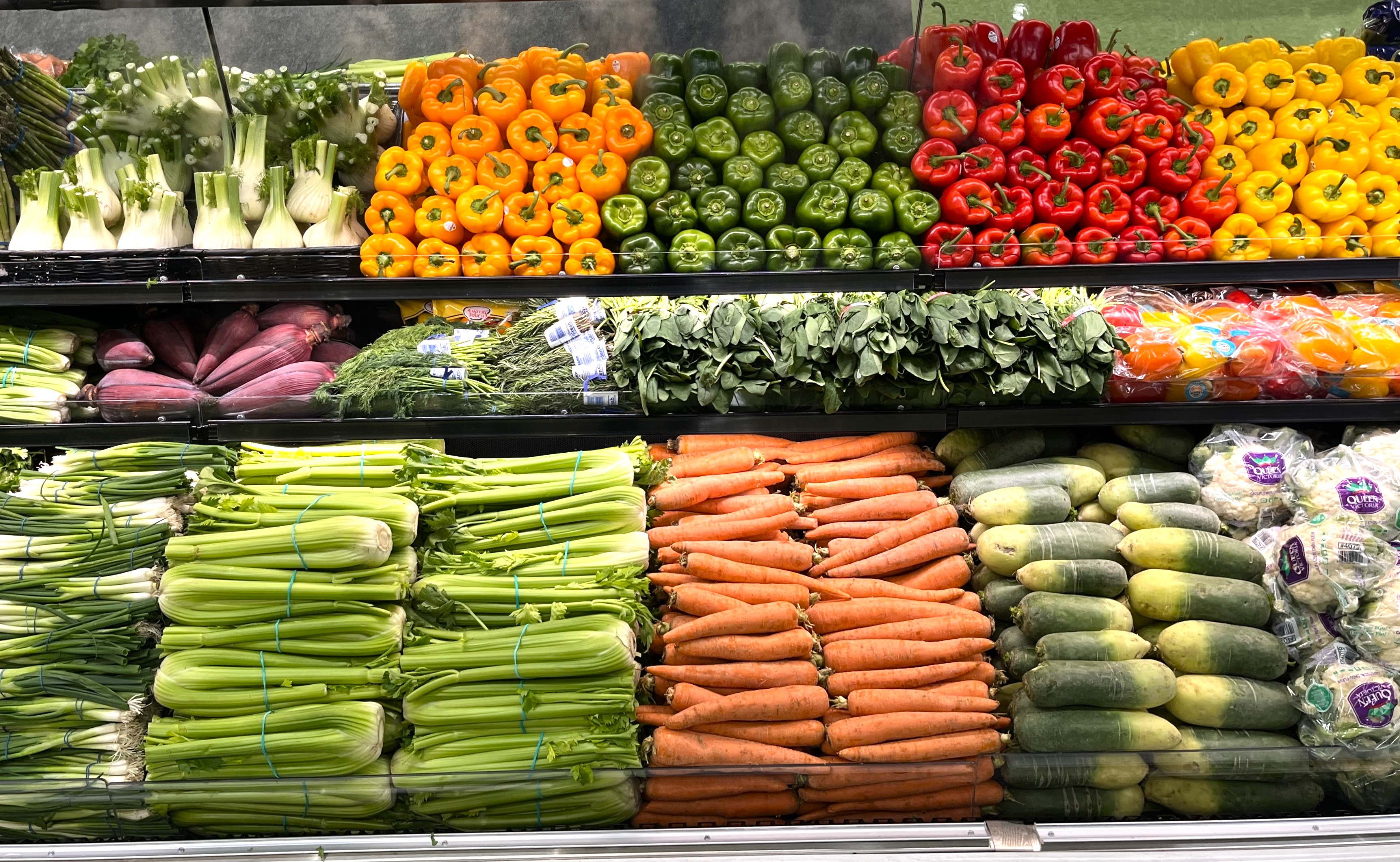 Color blocking technique is used in a produce department in vertical stacks of different types and color of veggies